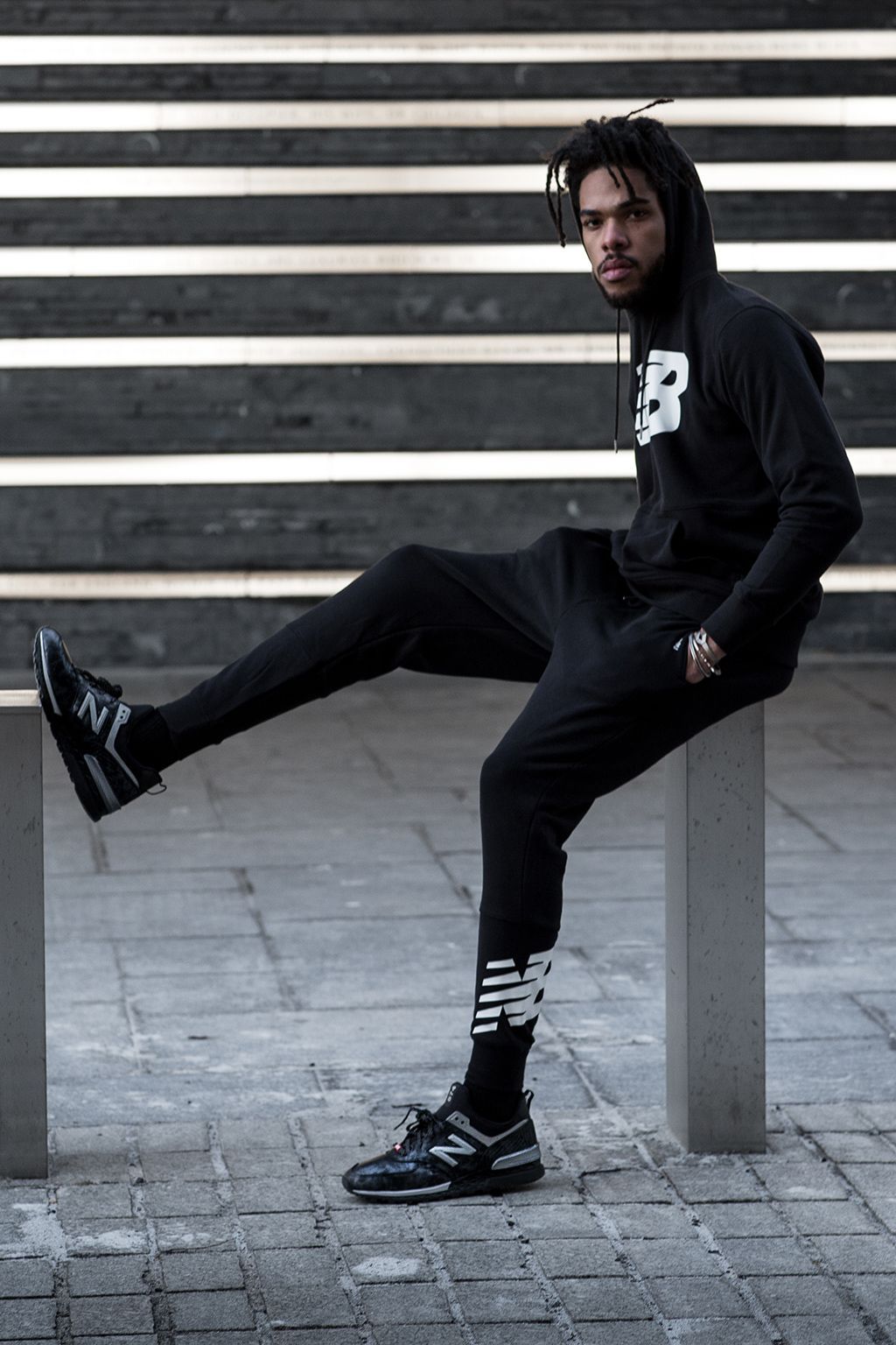 Evening photograph of male model posing with Black Panther New Balance shoes